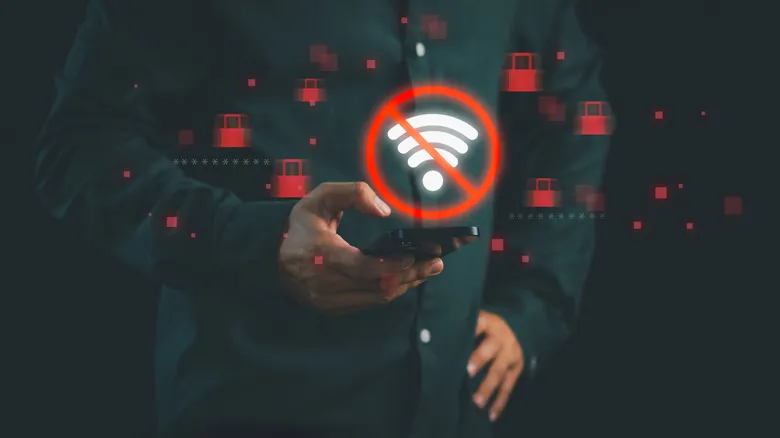 A glowing no Wi-Fi symbol and several lock symbols floating around a phone being held by a person